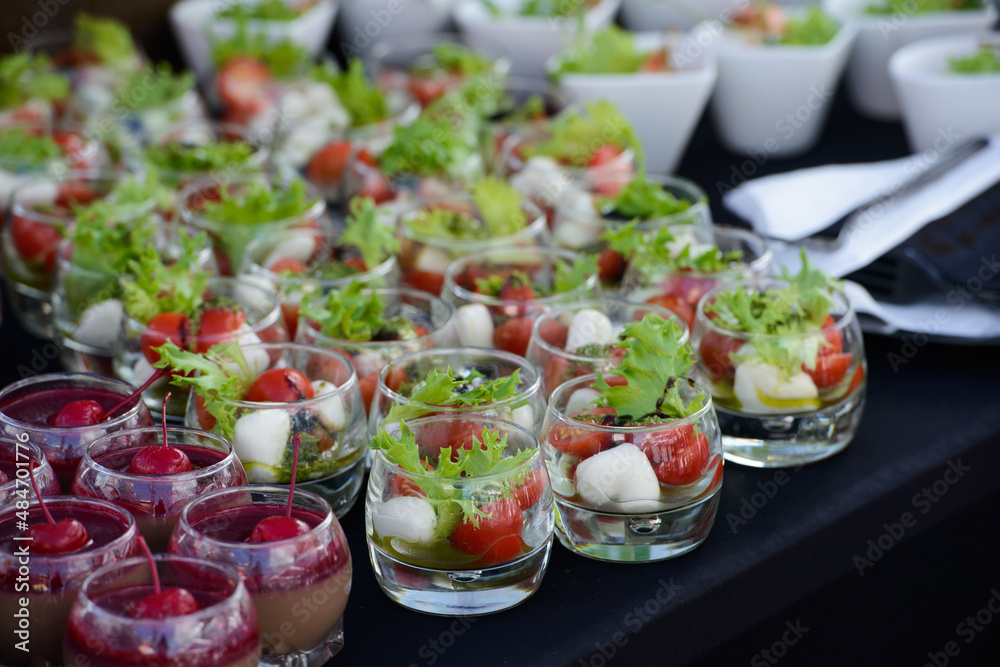 Small portion of Greek salad with tomatoes cherry in a glass, close up