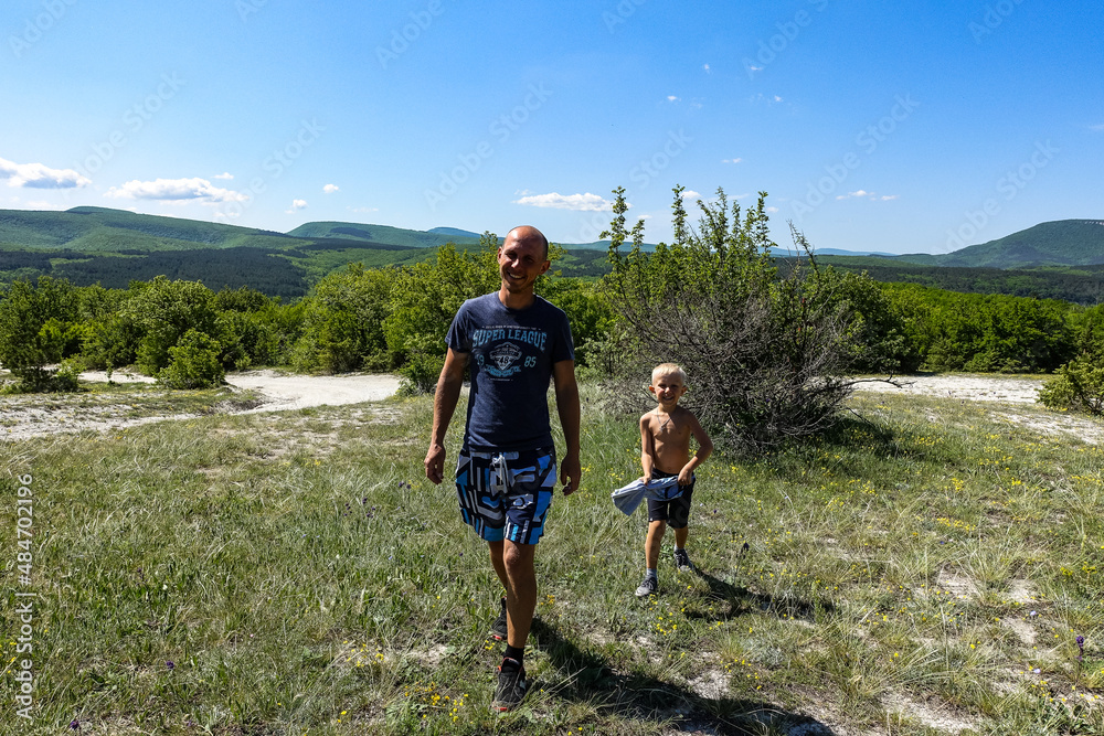 A man with a child on the background of the Crimean mountains near the cave town of Tepe-Kermen. Crimea. Russia.