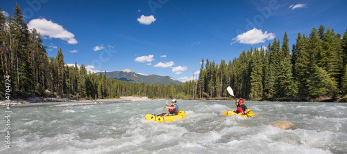 Panoramic view of two paddlers packrafting scenic river, B.C. Canada. photo