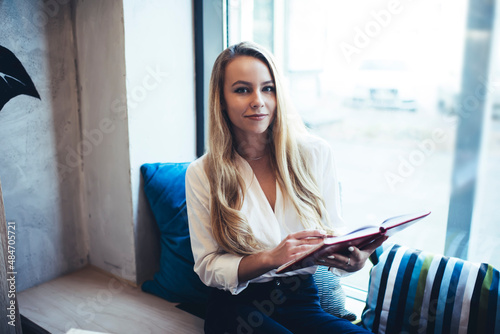 Woman with book near window in cafeteria