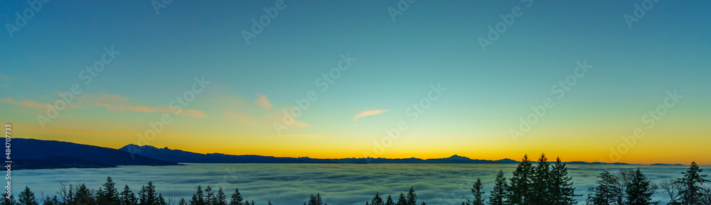 Beautiful panoramic sunrise over cloud-covered valley during a winter inversion, with mountain backdrop.