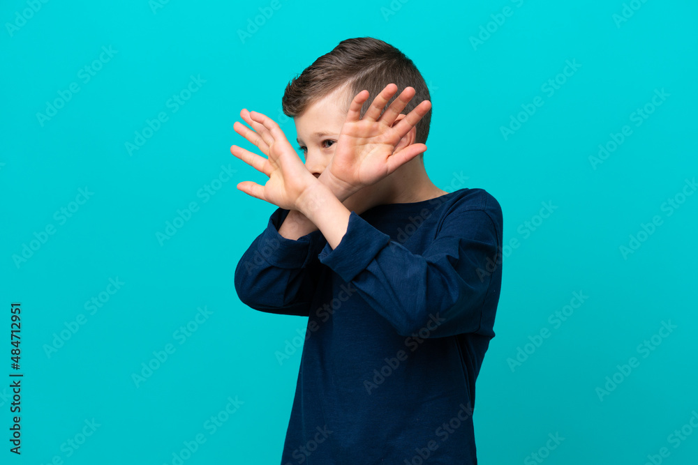Little kid boy isolated on blue background nervous stretching hands to the front