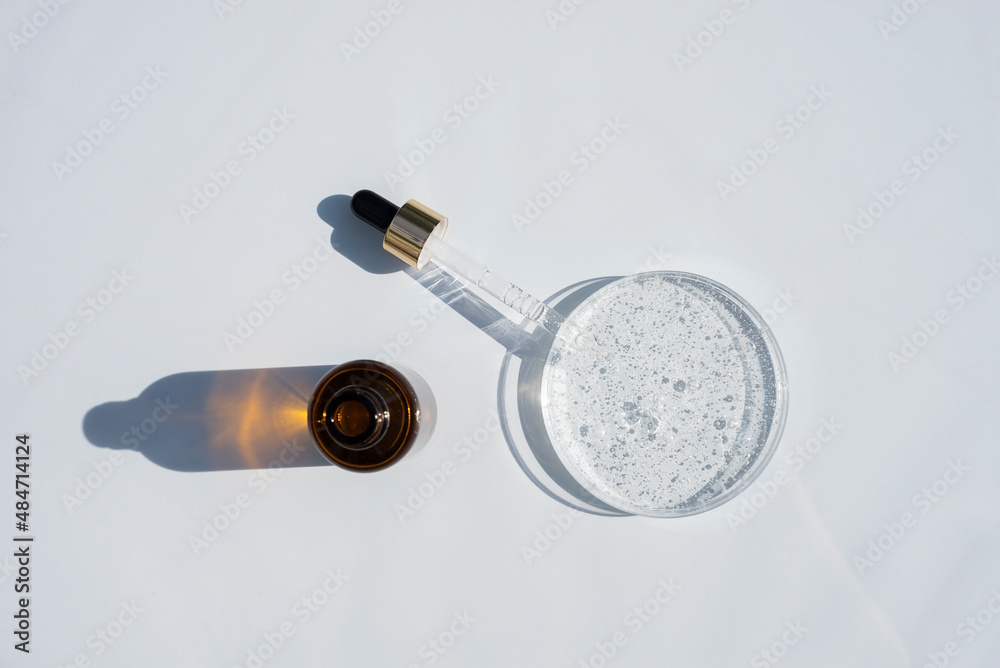 Open dropper bottle and cap with dropper pipette with serum and petri dish on light background. Transparent container with liquid and bubbles. The appearance of the texture of the gel. Medicine and Open dropper bottle and cap with dropper pipette with serum and petri dish on light background. Transparent container with liquid and bubbles. The appearance of the texture of the gel. Medicine and