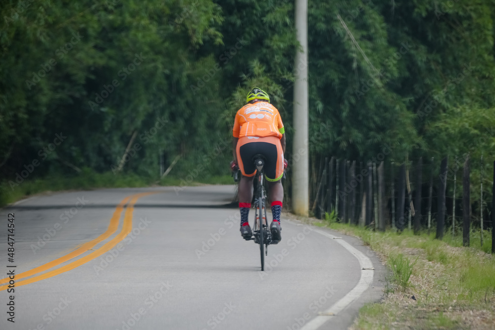 Fototapeta premium Ciclista na bicicleta andando com equipamento na estrada para corrida.