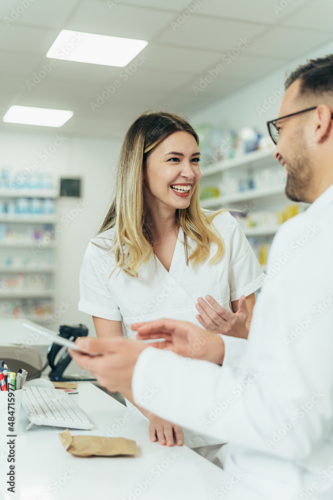 Obraz premium Happy young male and female colleagues pharmacist working in a pharmacy