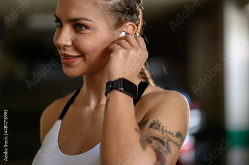 Woman in sportswear putting airpods in her ears before training
