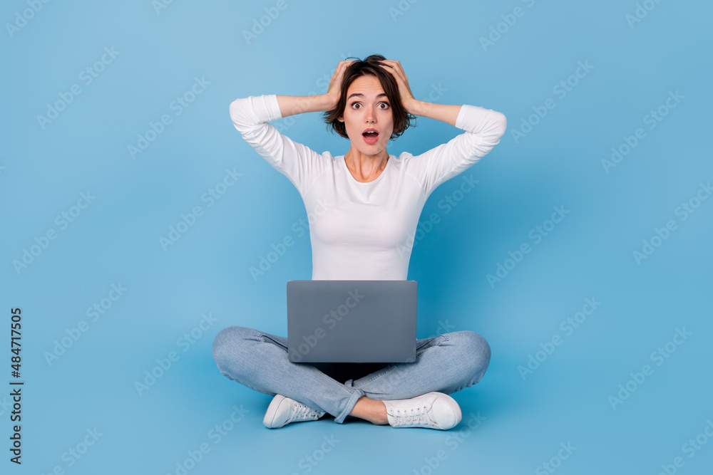 Photo of shiny impressed woman wear white shirt legs crossed reading modern gadget isolated blue color background Photo of shiny impressed woman wear white shirt legs crossed reading modern gadget isolated blue color background