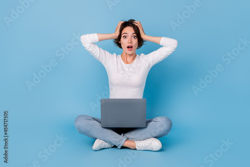 Photo of shiny impressed woman wear white shirt legs crossed reading modern gadget isolated blue color background