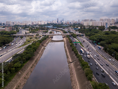 Beautiful drone aerial view of Marginal Tiete river avenue, Sao Paulo city skyline on summer sunny day. Cars, trees and buildings. Concept of urban, metropolis, architecture, pollution, climate.