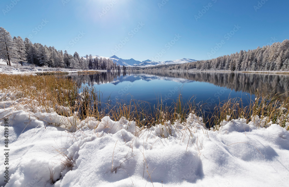 Forest lake in winter on the background of the Altai Mountains.