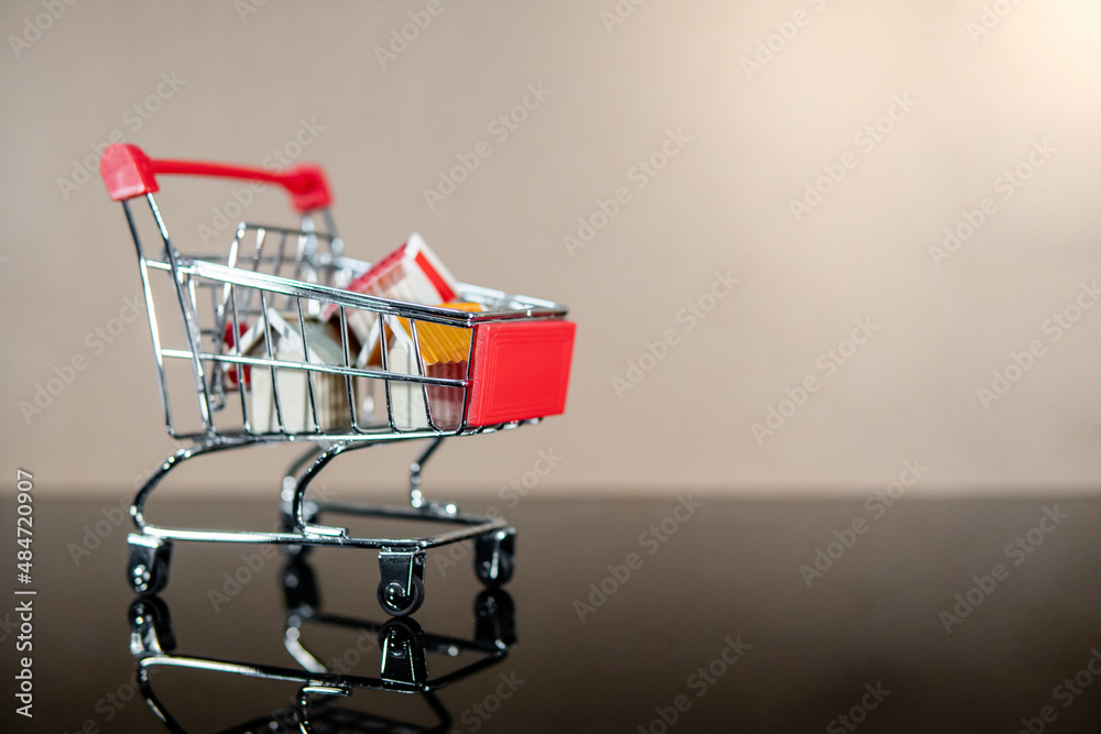 Buying property or real estate investment concept. Home mortgage and lease. Bank loan interest rate. Wooden house models in mini shopping cart on glossy table.