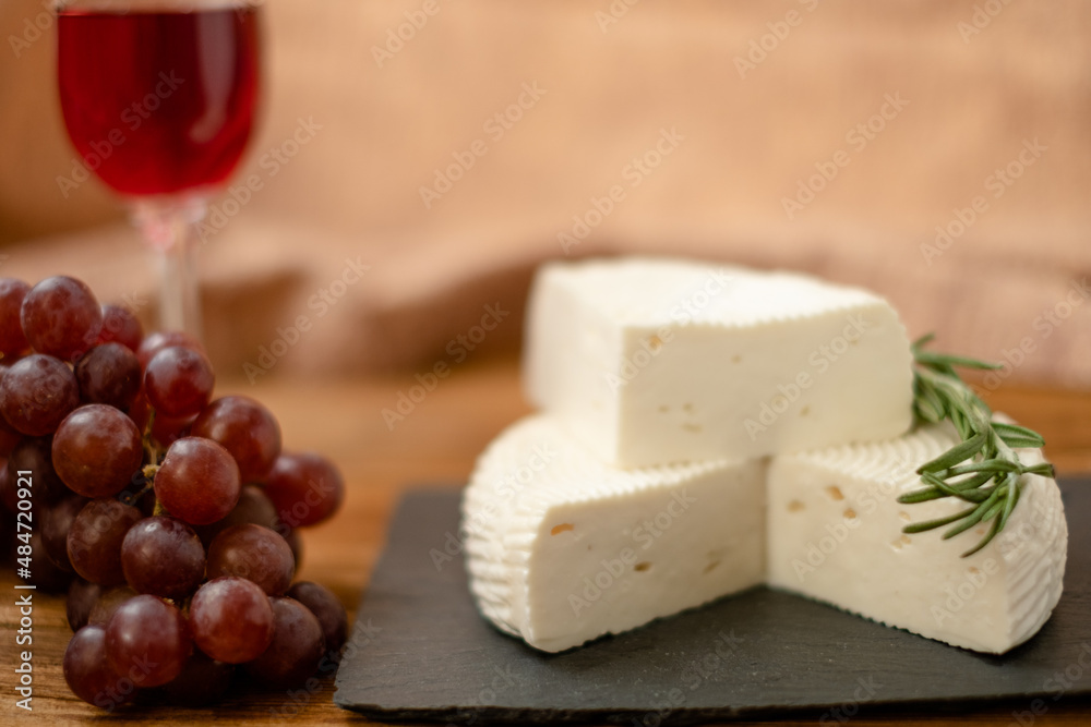 Goat cheese, grapes and wine lie on a wooden table. Cheese at home. Goat cheese, grapes and wine lie on a wooden table. Cheese at home.