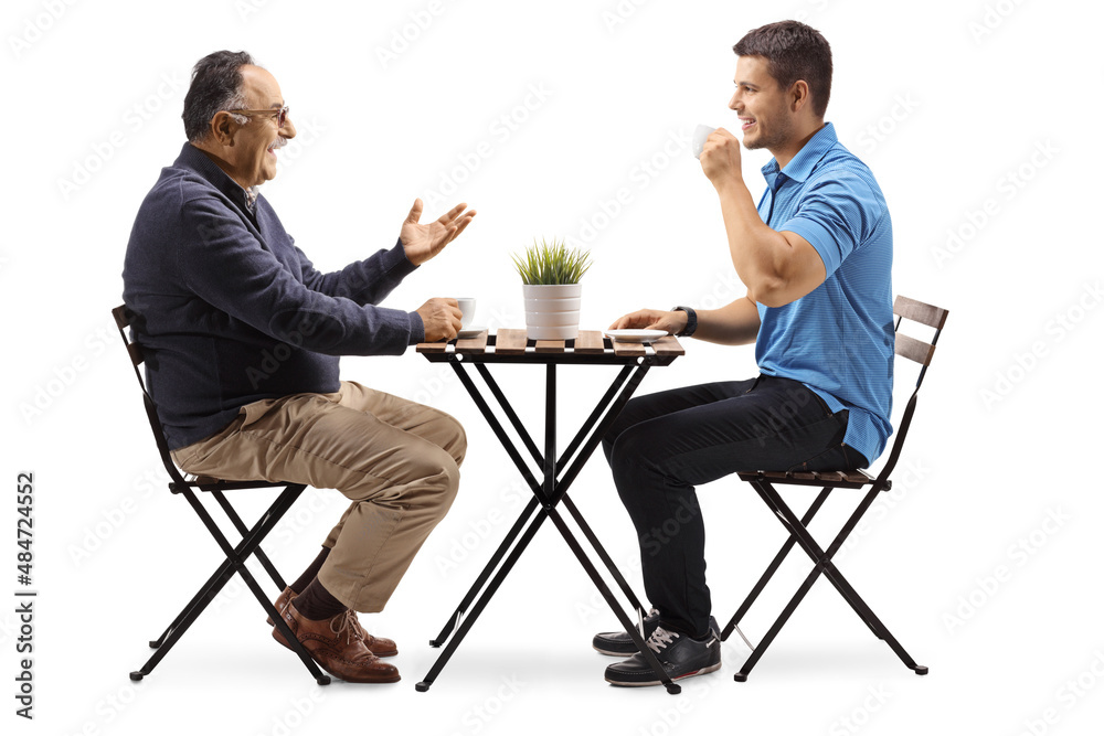 Obraz premium Young and mature man seated at a table and having a coffee