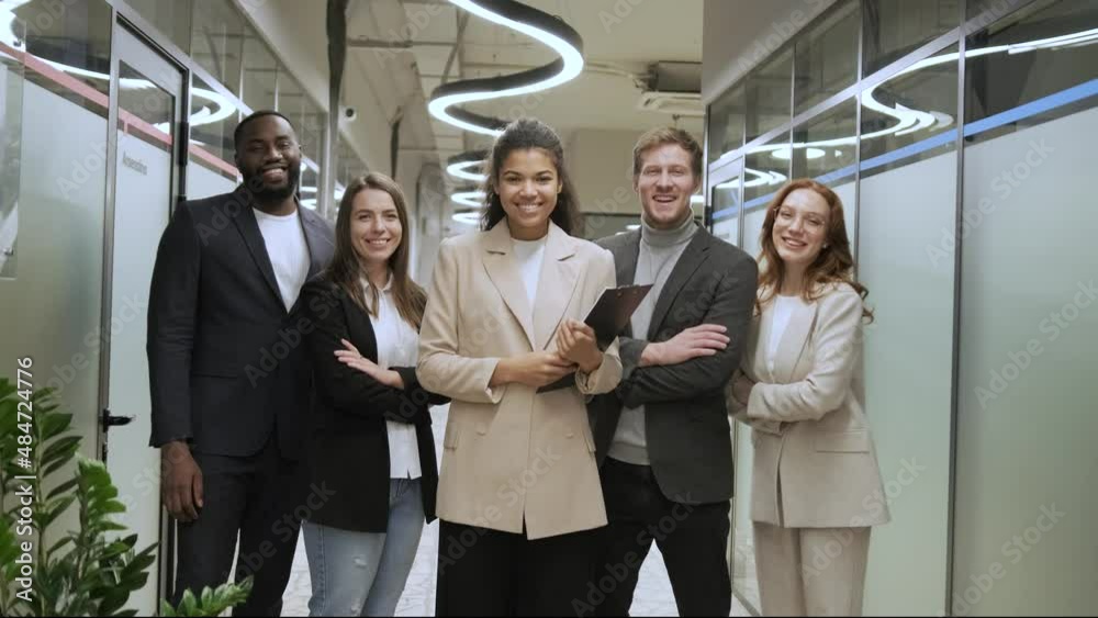standing in row smiling diverse team employees in the office looking at camera. Happy young multiethnic corporate staff standing in row smiling diverse team employees in the office looking at camera. Happy young multiethnic corporate staff