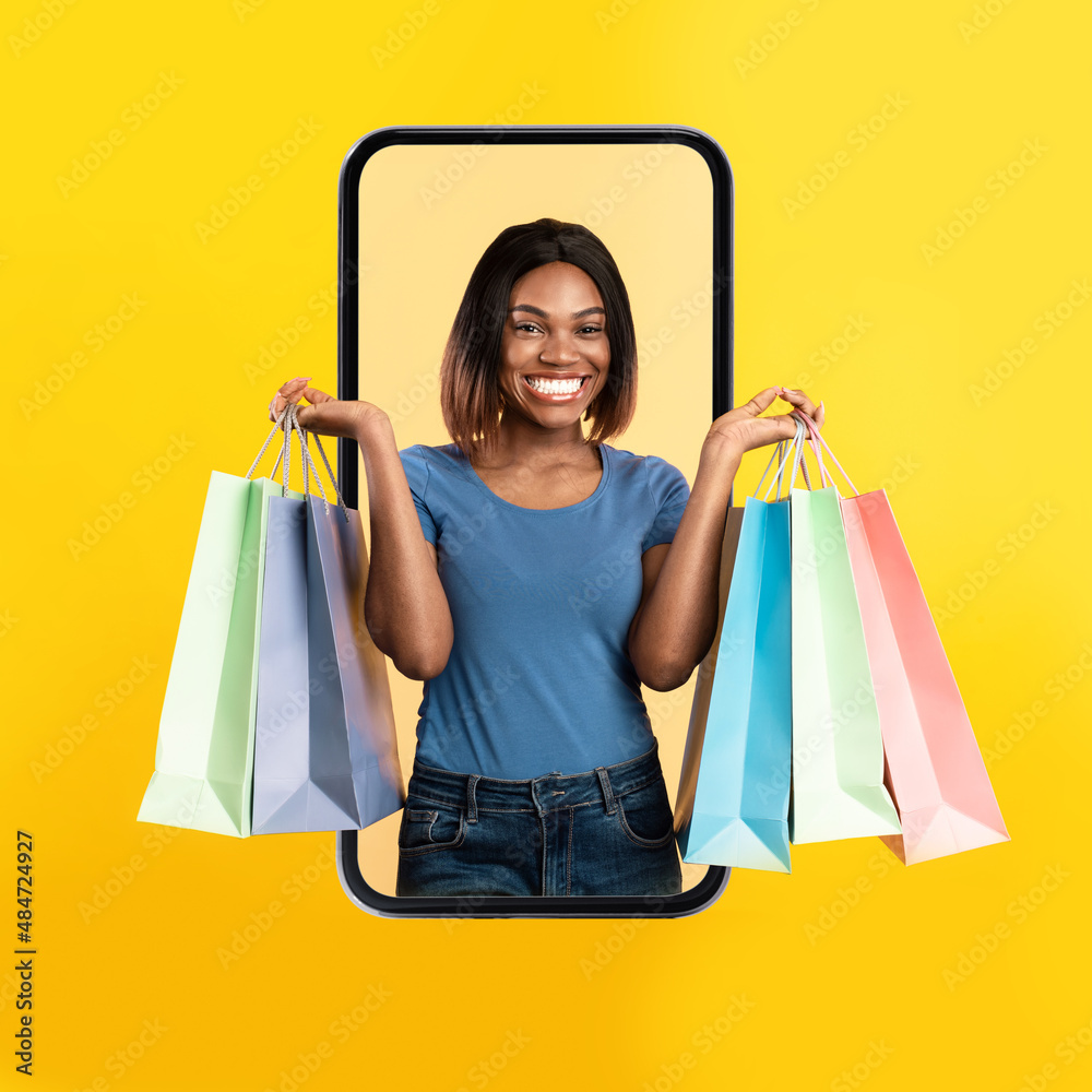 Excited black woman coming out screen with shopping bags Stock Photo ...