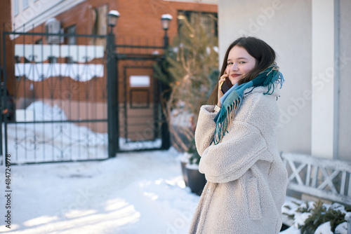 Smiling young woman is talking on the smartphone, snow around her