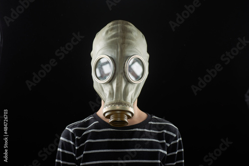Portrait of a boy in a gas mask on a dark background