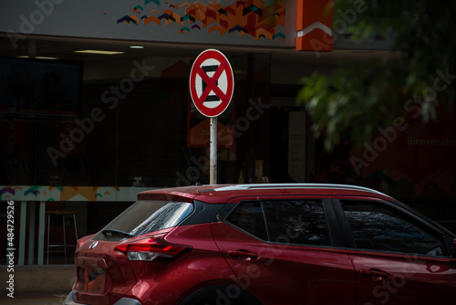Red vehicle committing an infraction and parked in the no parking and stop zone.
