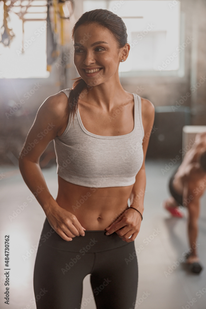 Beautiful female with perfect slim body wearing workout wear looking away  and smiling while posing in sports club Stock Photo | Adobe Stock