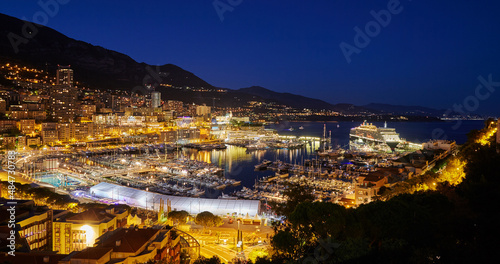 Aerial view of port Hercules in Monaco - Monte-Carlo at dusk, a lot of yachts and boats are moored in marina, cityscape with night illumination, magic reflection on water, mountain, mediterranean sea © Vladimir Drozdin