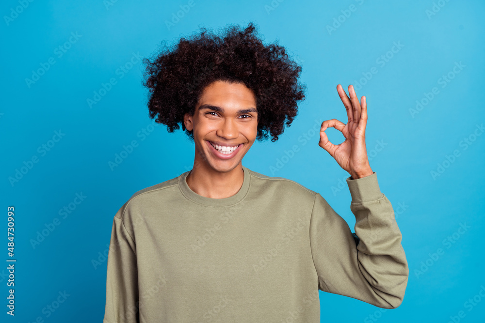 Photo of young man show fingers okey symbol great decide recommend ads isolated over blue color background Photo of young man show fingers okey symbol great decide recommend ads isolated over blue color background