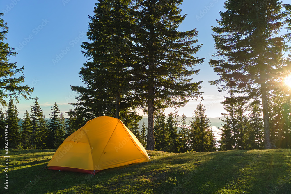 Tourist camping tent on mountain campsite at bright sunny evening. Active tourism and hiking concept