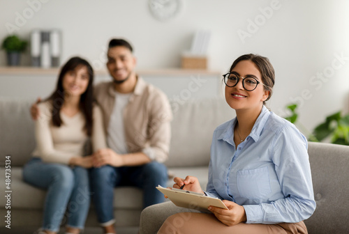 Successful family psychotherapy. Portrait of arab female marital counselor at office after effective session with couple photo