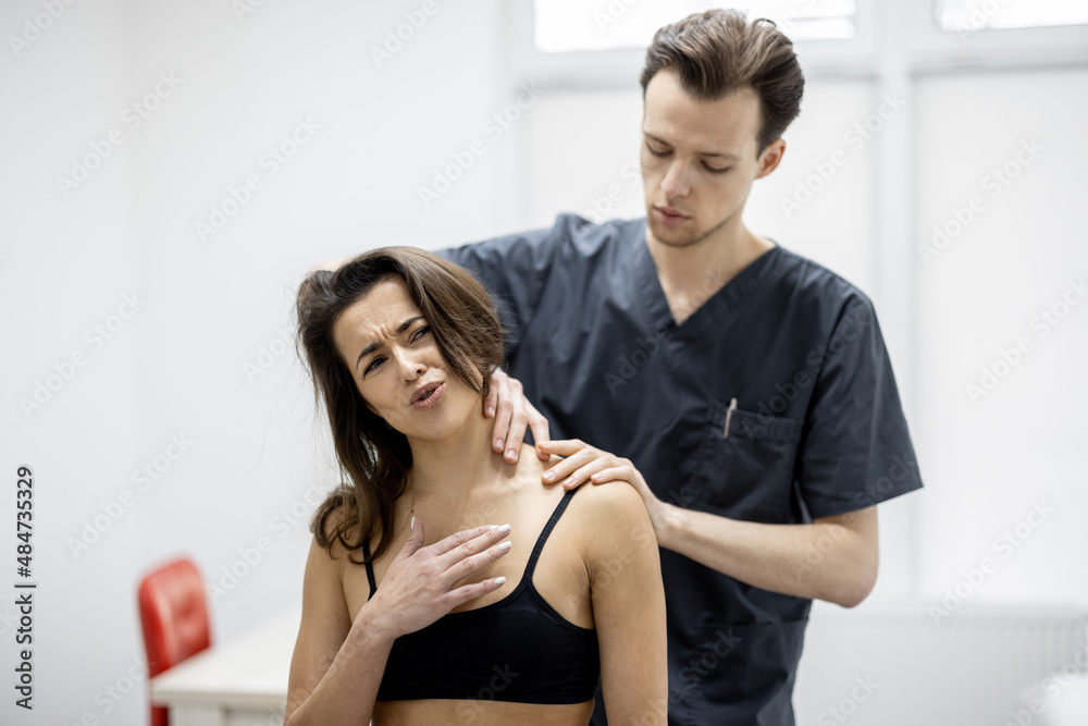 Physical therapist examines a woman in detail for musculoskeletal disorders in medical office. Female patient with complaints of back pain at physiotherapeutic appointment Physical therapist examines a woman in detail for musculoskeletal disorders in medical office. Female patient with complaints of back pain at physiotherapeutic appointment