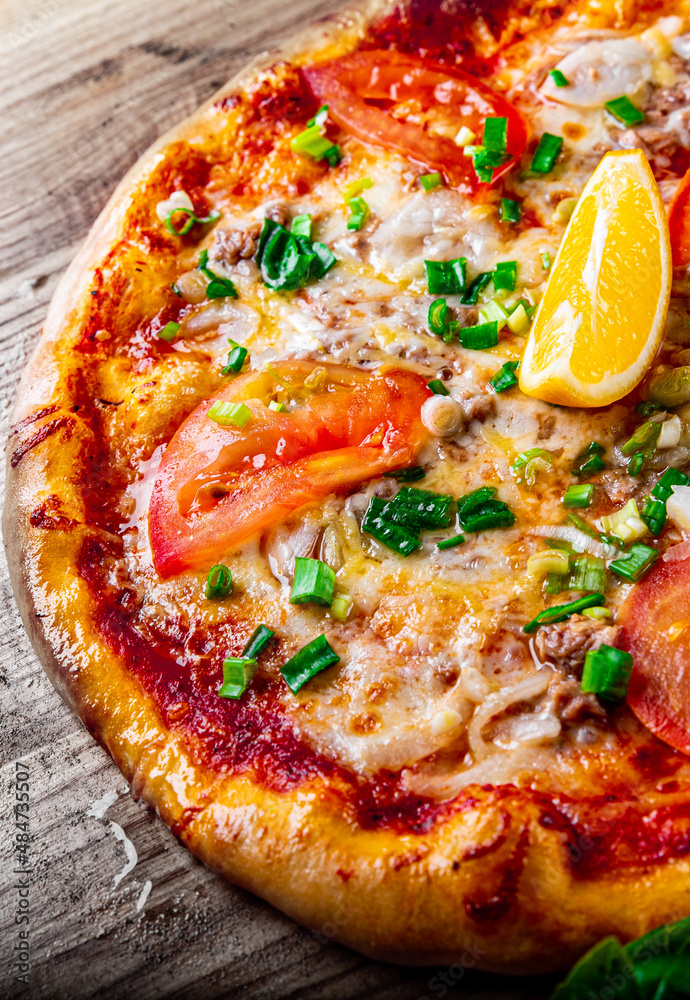 delicious pizza with tuna fish and lemon on wooden background delicious pizza with tuna fish and lemon on wooden background