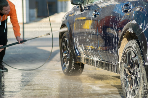 Young driver man washing his car with contactless high pressure water jet in self service car wash © bilanol