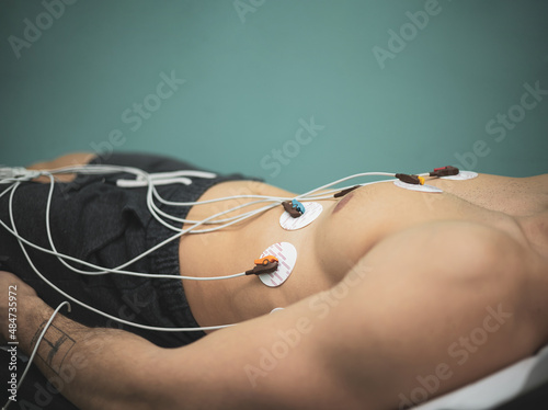 doctor with electrocardiogram equipment doing cardiogram test to male patient in hospital clinic
