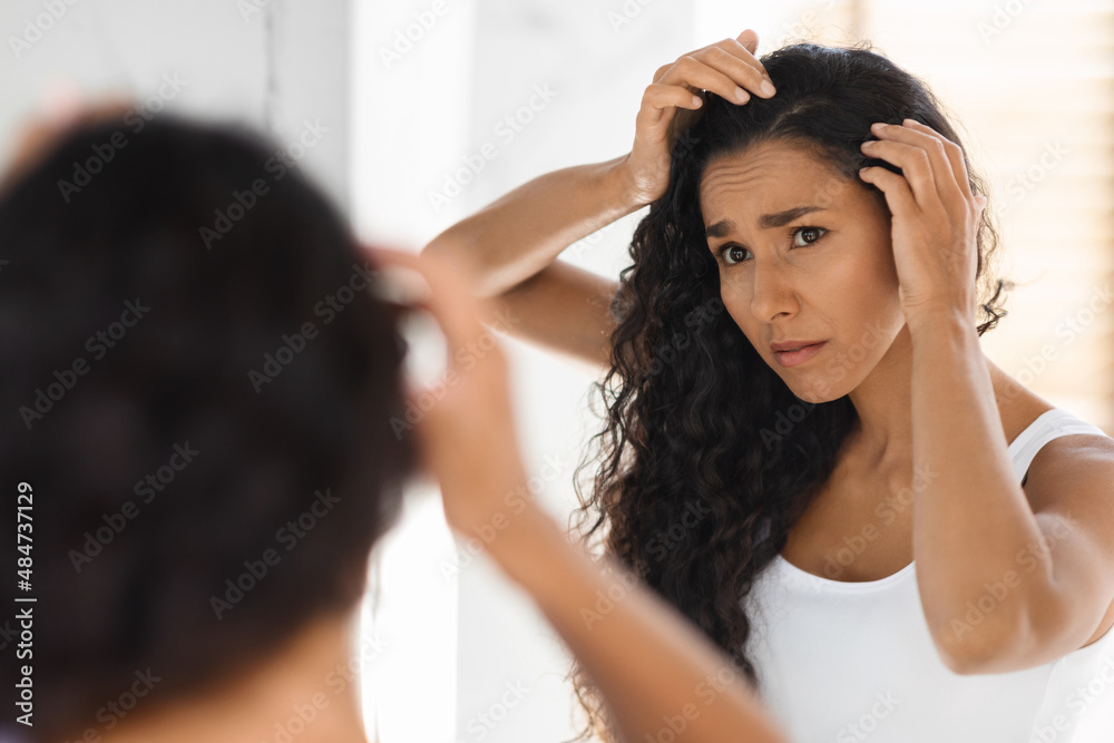 Fototapeta premium Dandruff Problem. Upset Young Female Looking At Hair Roots In Bathroom