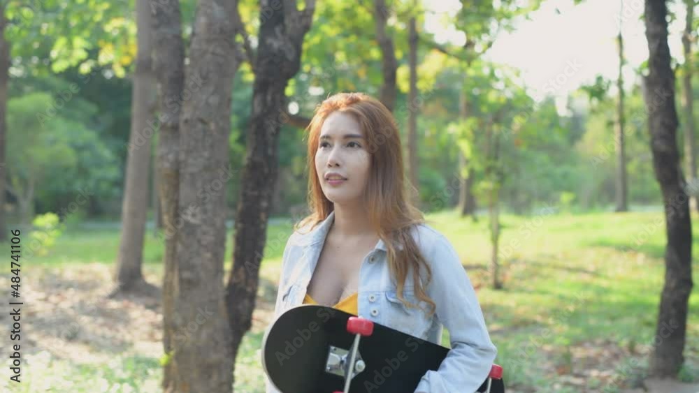 Independent concept of 4k Resolution. Asian woman holding a skateboard in the park. Independent concept of 4k Resolution. Asian woman holding a skateboard in the park.