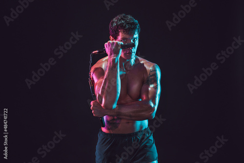 Half length of man who trains with nunchaku while isolated on black background. Sport concept