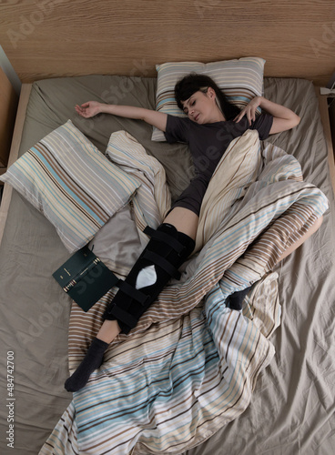 Woman with ACL surgery sleeping in bed at home.