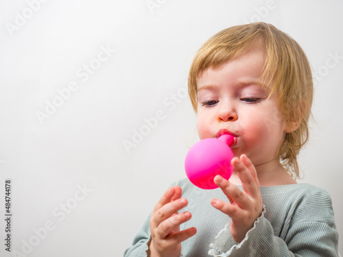 little girl trying to inflate a balloon with her lips