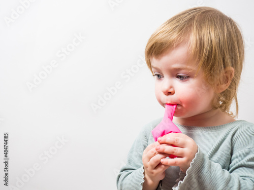 little girl trying to inflate a balloon with her lips