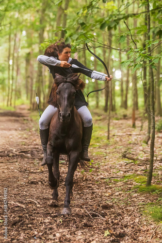 beautiful woman with long hair woman on a horse shooting a bow © michal