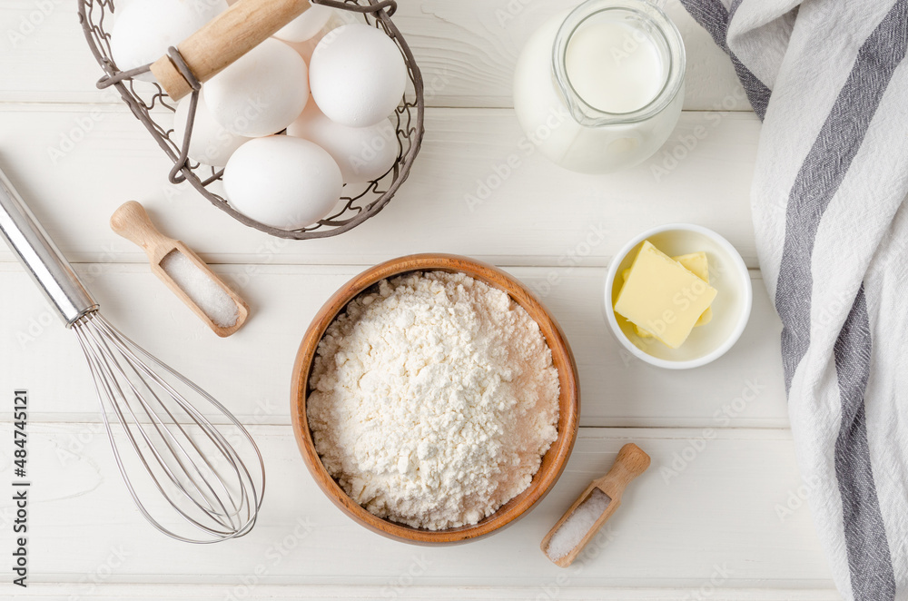 Ingredients for making traditional thin pancakes or crepes on a white wooden background. Recipe step by step. Food for Maslenitsa. Ingredients for making traditional thin pancakes or crepes on a white wooden background. Recipe step by step. Food for Maslenitsa.