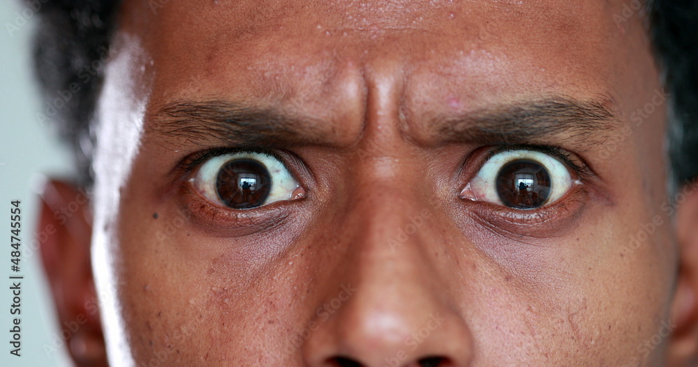 Surprised African descent close-up eyes reaction, looking to camera. Back person eye SHOCK - obrazy, fototapety, plakaty 
