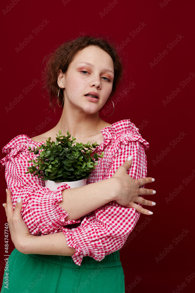 woman in pink blouse flower potted posing red background unaltered woman in pink blouse flower potted posing red background unaltered