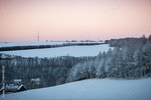 Winter above ice cold city of Chemnitz, Germany. Frozen hoar frost trees and forests covered in snow. Violett sky over industrial town in Saxony. Panoramic view from Einsiedel, Erfenschlag.