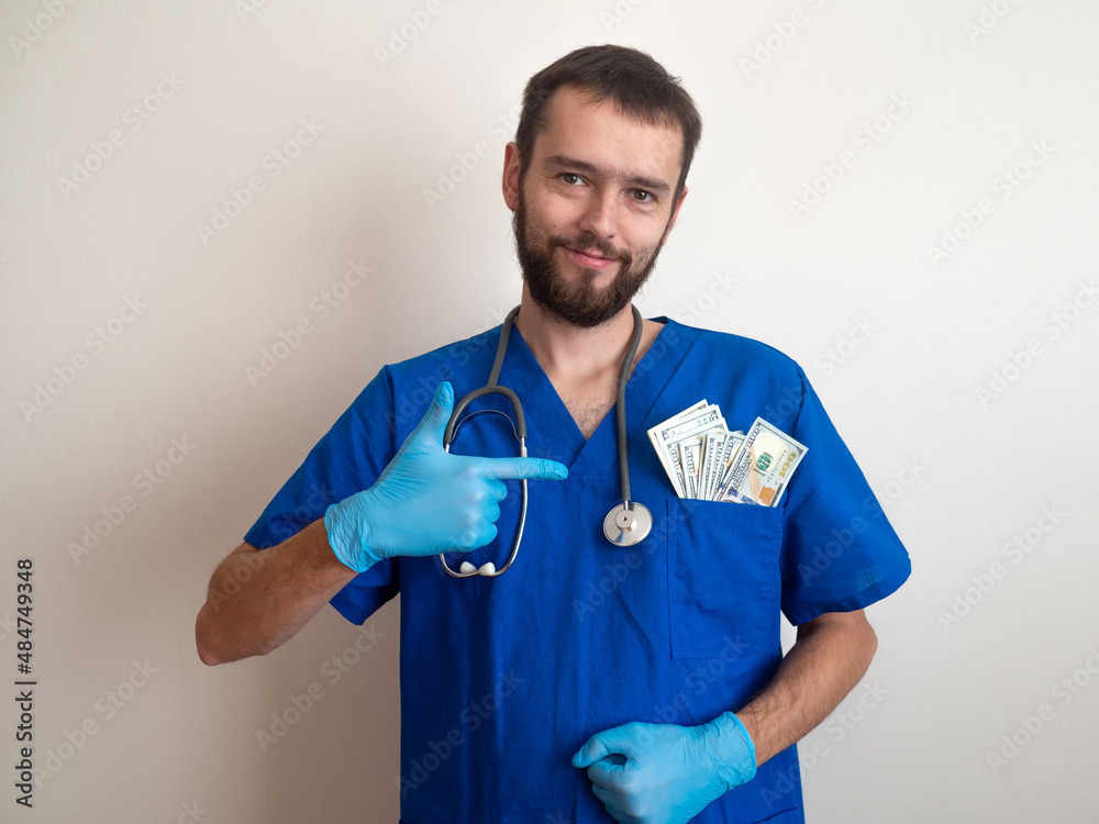 Male medicine doctor holding money dollars banknotes in pocket. Payment salary for the doctor and nurses work. Payment to Employees in the red zone. Award to doctors working with covid patients Male medicine doctor holding money dollars banknotes in pocket. Payment salary for the doctor and nurses work. Payment to Employees in the red zone. Award to doctors working with covid patients