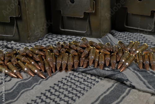 .308 caliber ammunition and ammunition containers on a green-gray fabric background (keffiyeh) photo