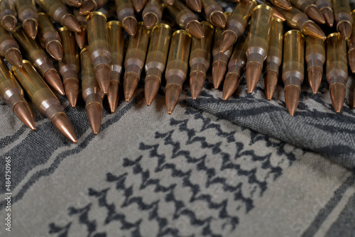 .308 caliber ammunition on a green-gray fabric background (keffiyeh) photo