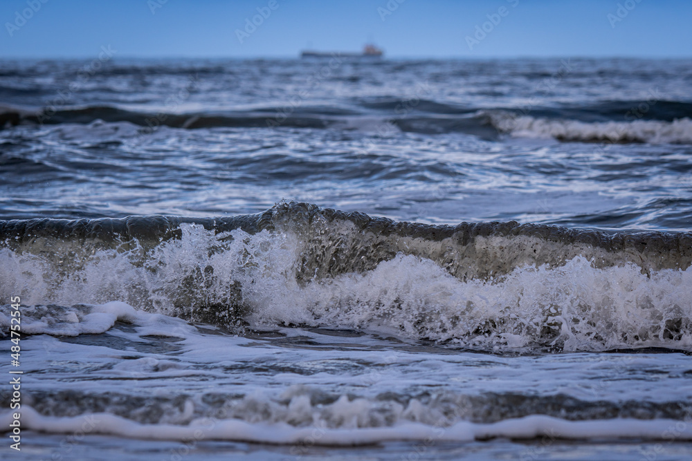 View of the Baltic Sea from the beach with the ship blurred in the background

