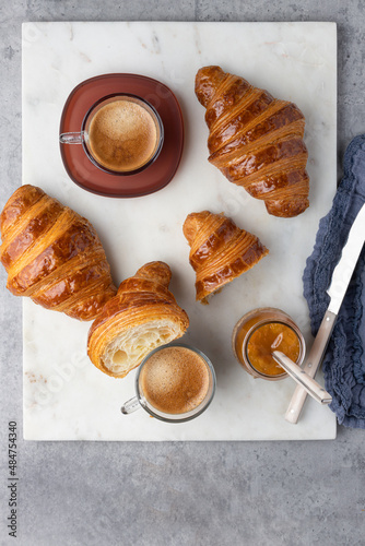 Overhead view of a breakfast clean scene with some brilliant croissants and two coffees over a marble board.