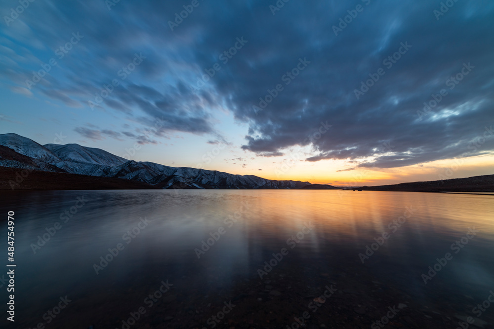 Beautiful long exposure landscape. Small lake and mountains after sunset with dramatic clouds.