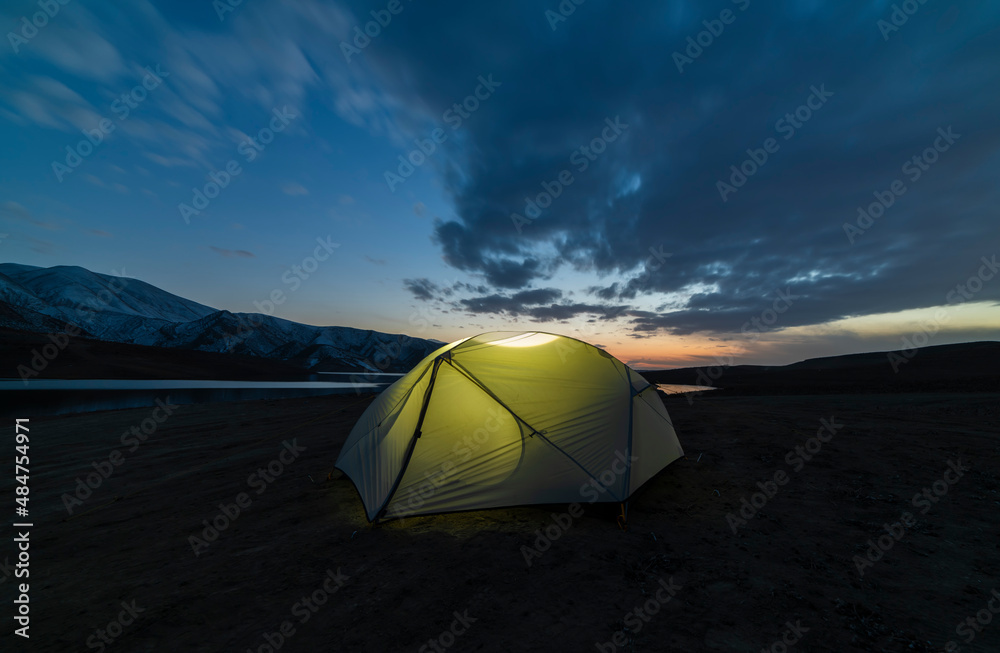 Tent on the beach. Camping in the mountains near the lake after sunset.