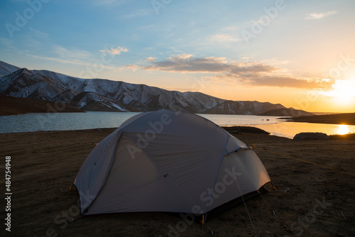 Tent on the beach. Camping in the mountains near the lake at the sunset.